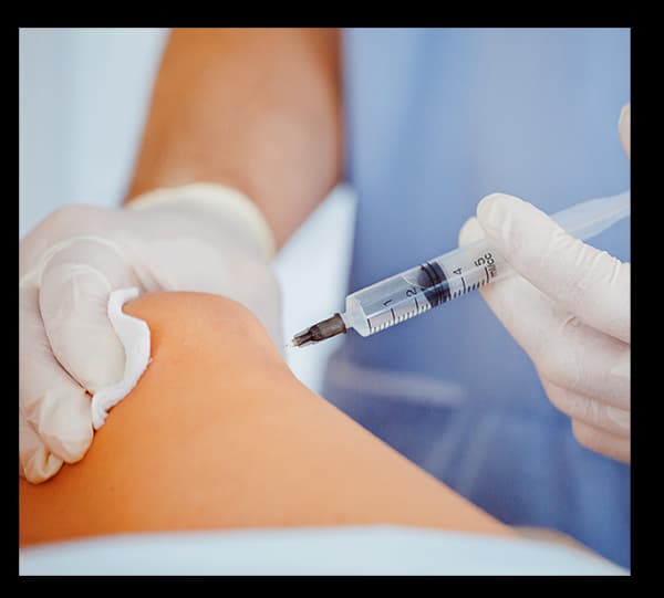 A person wearing white gloves is administering an injection into a patient's arm, with a cotton ball placed on the site after the injection.
